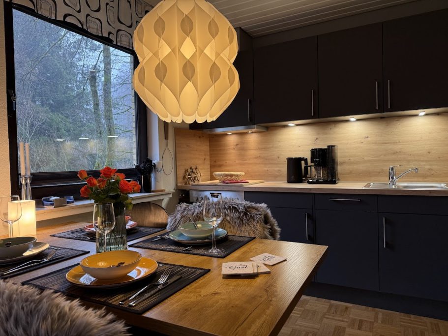 Neue Einbauküche mit Spülmaschine Moderne Küche mit Holzdetails, gemütlichem Essbereich und warmem Licht.